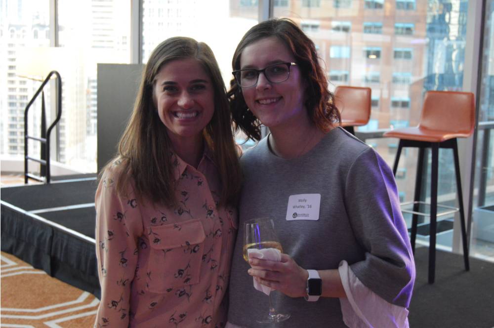 Two alumnae smile for a photo together while enjoying their drinks